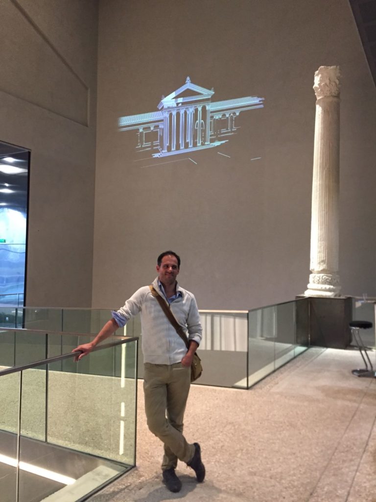 Hall du musée de la romanité. Pose devant une des colonnes du nymphée, et animation 3D en arrière-plan